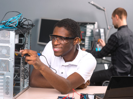 Homem jovem negro afro de óculos técnico em informática consertando computador