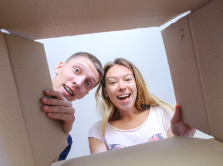 Casal abrindo caixa de e-commerce surpreso e sorrindo