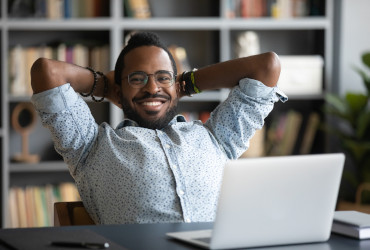 homem empresario negro afro de camisa relaxando em frente ao laptop