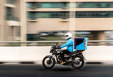 Motoboy de delivery de azul fazendo entrega de moto